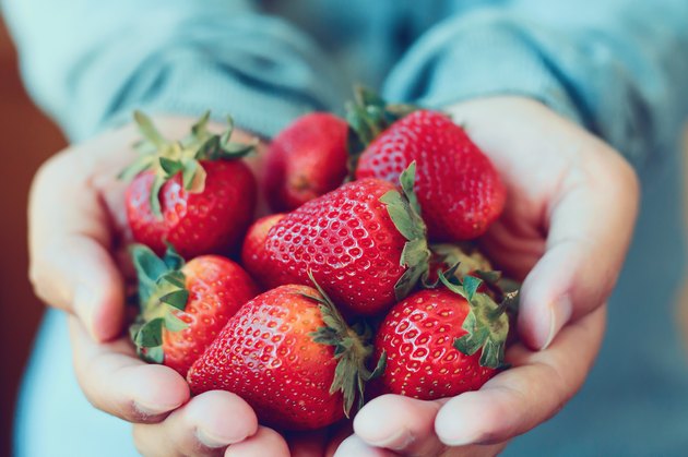 Hands holding a serving of fresh strawberries