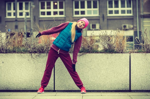 Sporty girl stretching outdoor on city street.