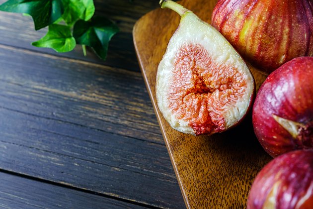 Fresh figs. Fruit with half isolated on wooden background.