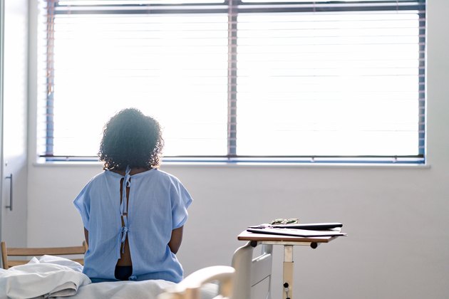 Lonely female patient looking through window