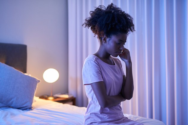 A woman with keto insomnia sitting on her bed in the middle of the night