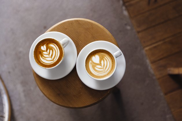 Directly above view of two coffee cups with latte art on the round table