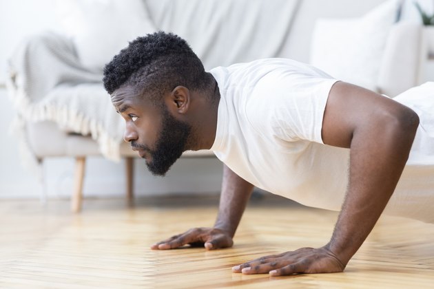 Young black man doing push ups, side view