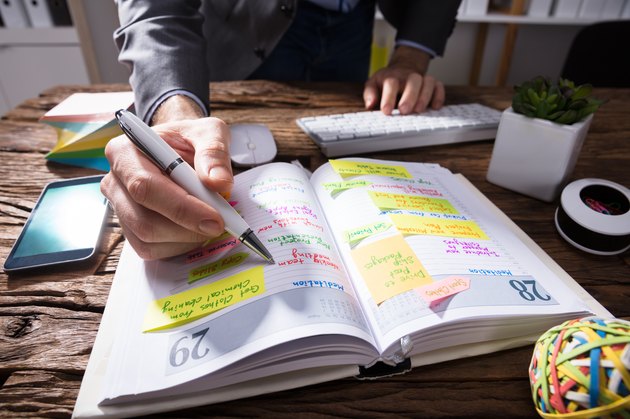 Businessperson's Hand Writing Schedule In Diary With Pen