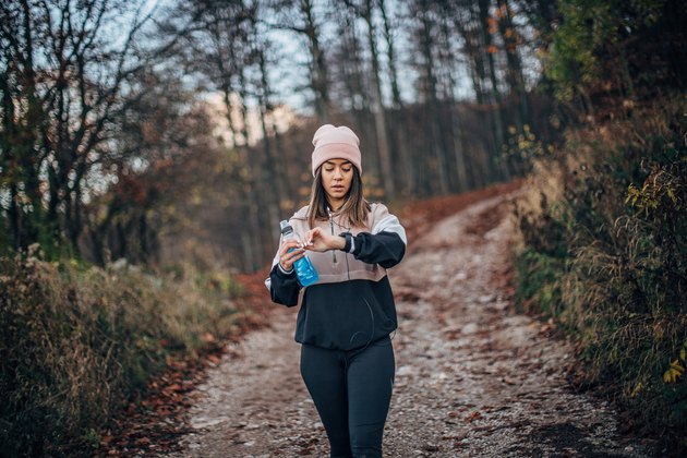 Young woman is walking and checking smart watch using app that pays you to walk
