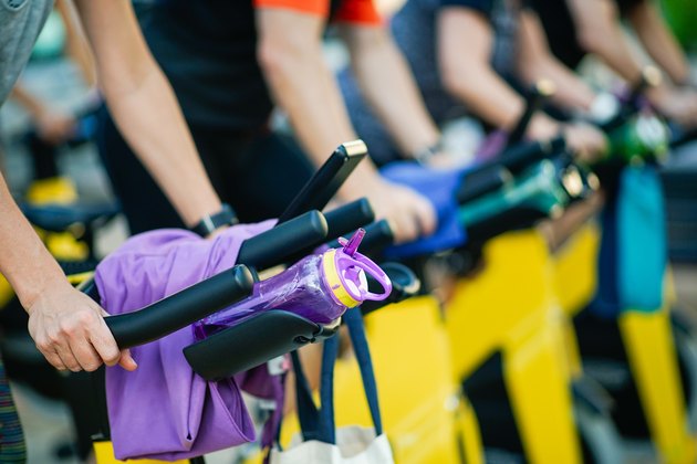 People Exercising On Exercise Bike At Gym