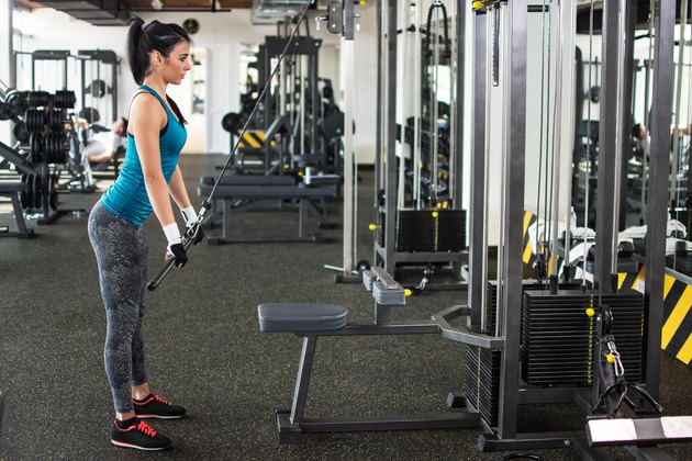 Beautiful girl doing triceps push down in gym.