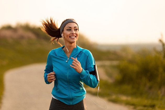 快乐的女跑步者早晨在大自然中慢跑。