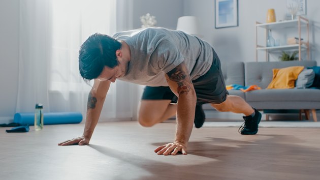 Athletic man doing mountain climber exercises at home