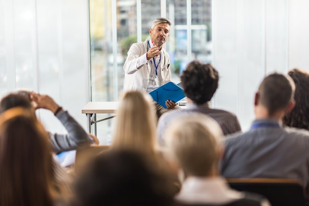Adult doctor teaching on a seminar in a board room.