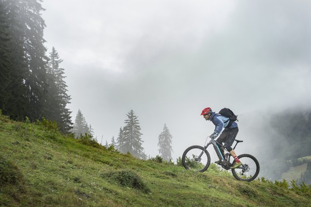 Man with Pedelec riding uphill in mountains, Saalfelden, Tyrol, Austria
