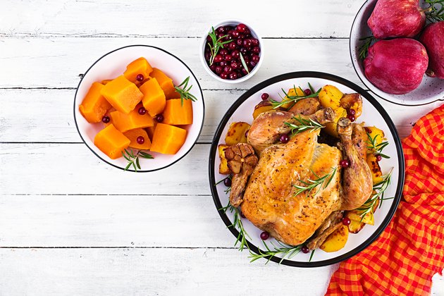 Roasted turkey garnished with cranberries on a rustic style table decorated autumn leaf. Thanksgiving Day. Baked chicken. Top view