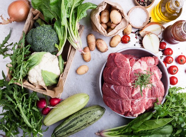 Cut of steak and variety of green vegetables and herbs