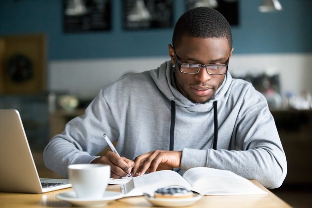 Focused man making notes while studying in cafe