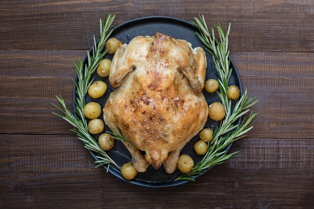 Traditional roasted turkey with rosemary on wooden table. Top view. Thanksgiving day.