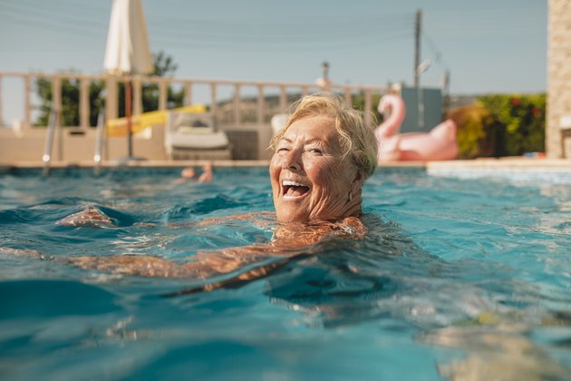 Woman treading water in her backyard pool during summer