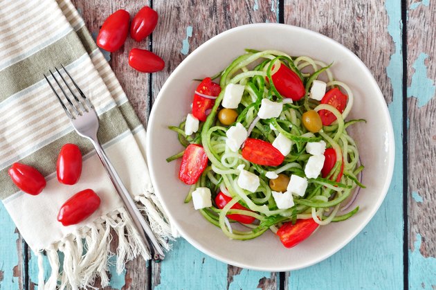 Greek Salad with cucumber noodles, overhead scene on rustic wood
