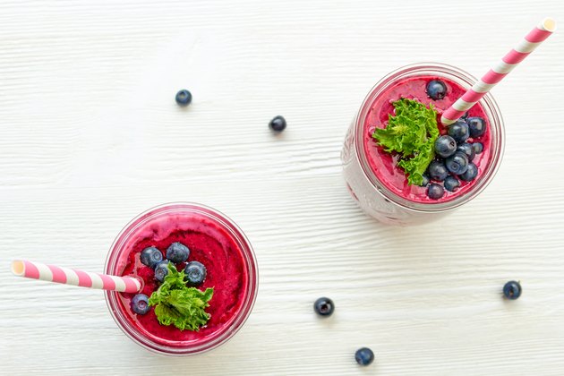 Two jars of blueberry smoothie on white wooden table