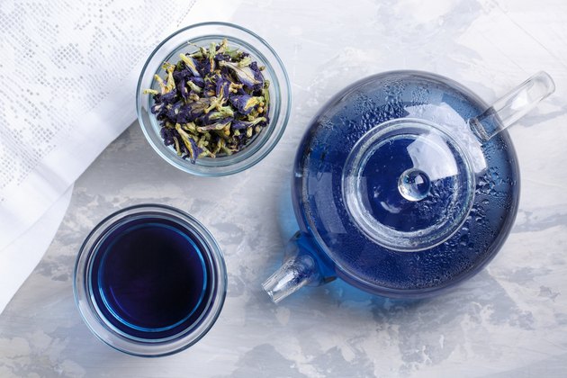 Butterfly pea flower tea is brewed in a glass teapot and served into a transparent cup. Blue herbal tea. Top view.