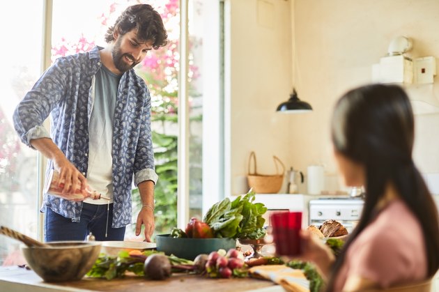 Friends cooking salad and adding gluten-free salad dressing.