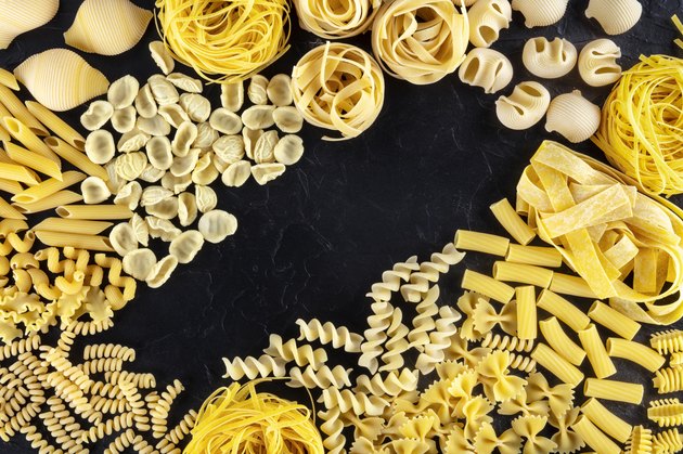 Italian pasta design with copy space, a flat lay of a variety of pasta types, shot from above on a black background with a place for text