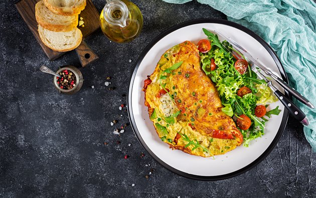 Breakfast. Omelette with tomatoes, avocado, blue cheese and green peas on white plate. Frittata - italian omelet. Top view