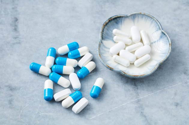 Tri-Creatine Malate and Arginine capsules and BCAA amino acids. Bodybuilding food supplements on bright stone background. Close up.