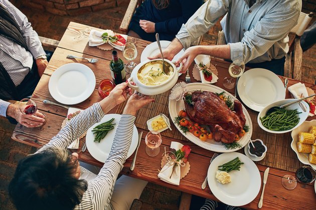 Top view of people passing food at a table set for Thanksgiving