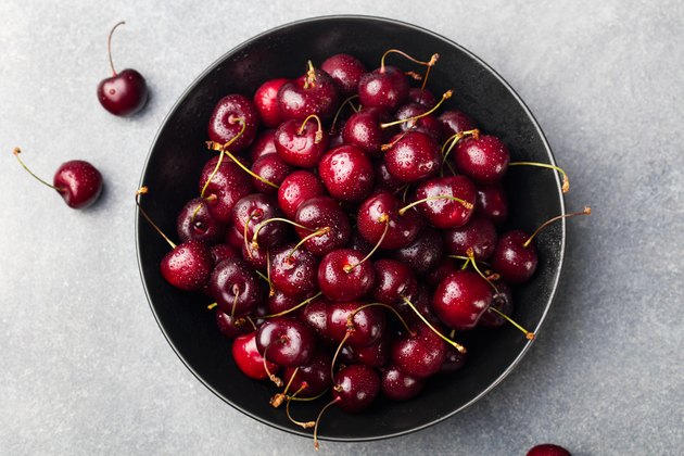 Fresh ripe black cherries in a black bowl, top view