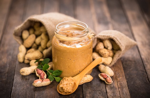 Peanut butter and peanuts on the wooden table for cheap protein