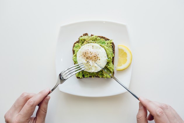Eating breakfast with avocado toast and egg from personal perspective point of view