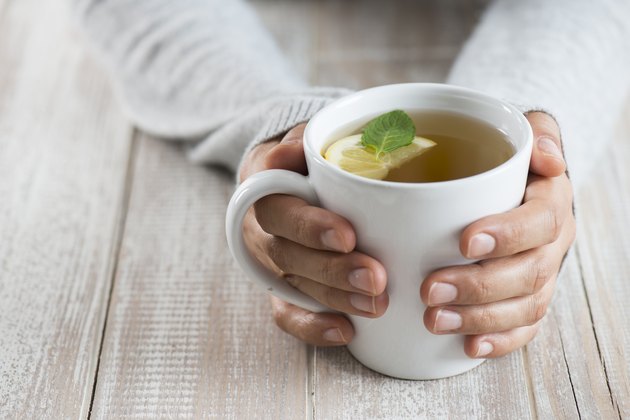 Die Hände einer Frau halten eine Tasse Senna-Tee als natürliches Heilmittel gegen Verstopfung