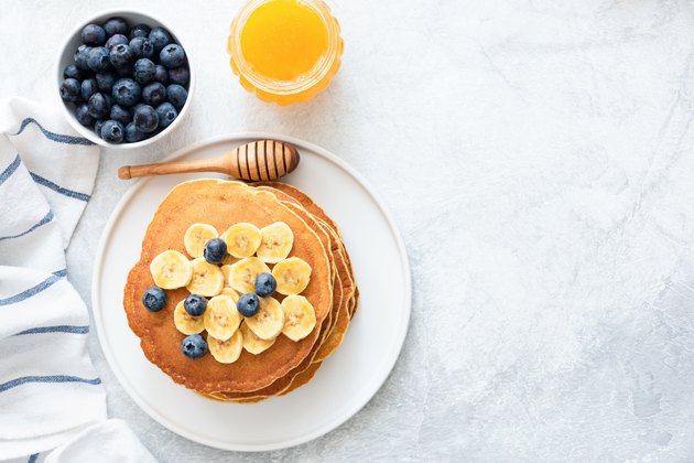 Buttermilk Pancakes with banana, blueberries and honey on concrete background