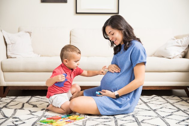 Innocent Boy Touching Abdomen Of Pregnant Mother At Home