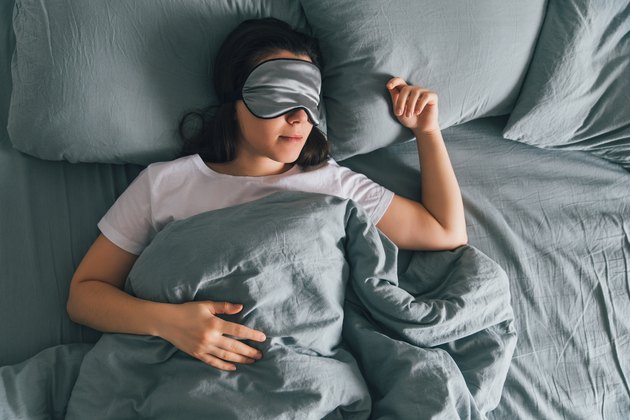 Woman asleep in bed with a mask over her eyes