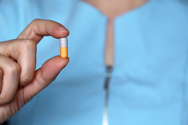 Doctor holding pill, capsule in female hand close-up