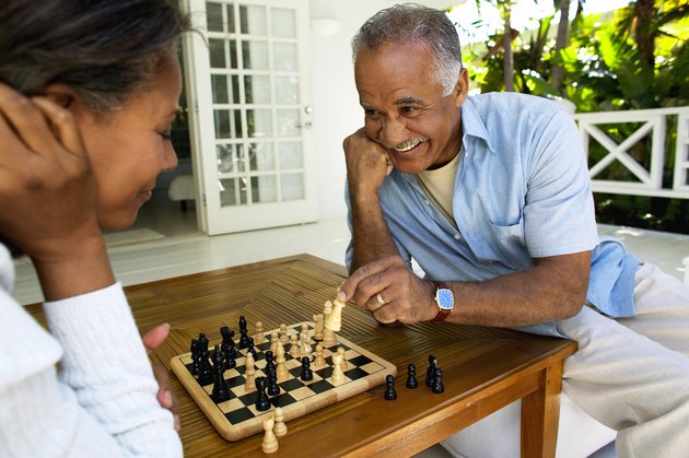 A husband and wife playing chess together at home