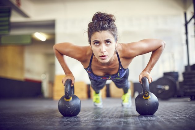 做在水壶的集中的运动员在健身房的kettlebell