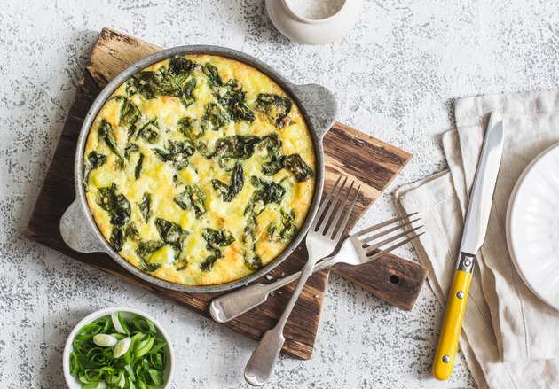 Potato and spinach tortilla in a pan on a light background. Delicious appetizer or snack, top view