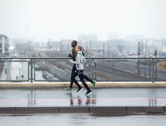 two friends jogging across urban street bridge