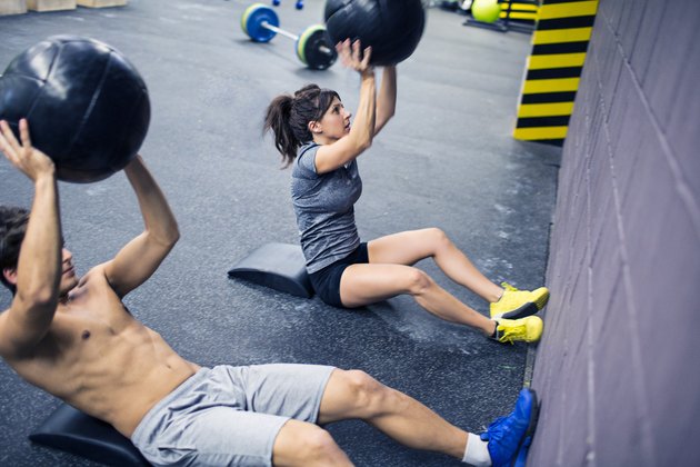 一个CrossFit类中男人和女人做健身球仰卧起坐