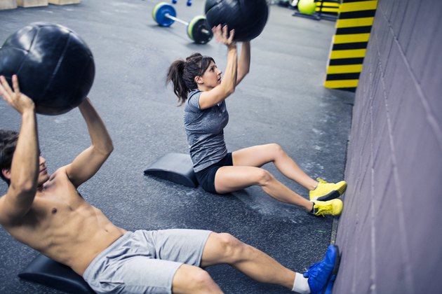 做医学球仰卧起坐的男人和妇女在一个crossfit类