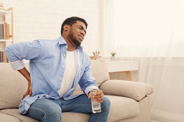 Young black man with back pain at home