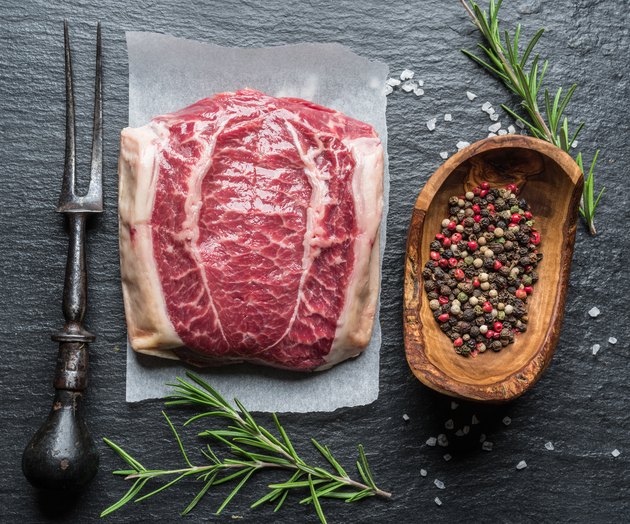 The top blade steak or beef steak on the graphite board with herbs and spices.