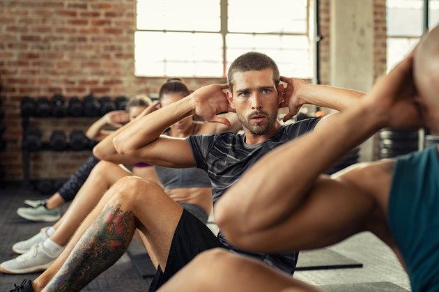 Fitness people in a row doing sit ups
