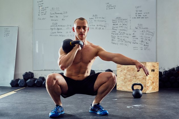 Young athletic man doing kettlebell squat exercise at the gym