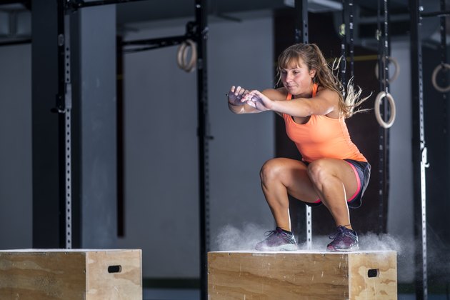 Athletic young woman doing box jump exercise at gym
