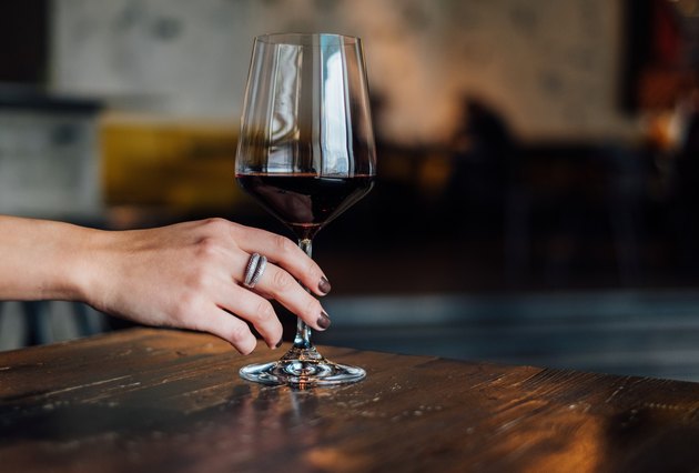 Plan de main tenant un verre de vin rouge sur table en bois