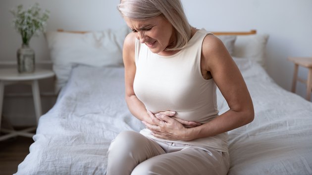 Woman holding belly, suffering from pain and thinking about foods to avoid with an upset stomach