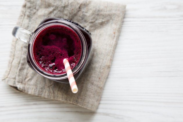 Glass jar of beetroot smoothie, top view. White wooden background. From above, overhead, flat lay. Copy space.